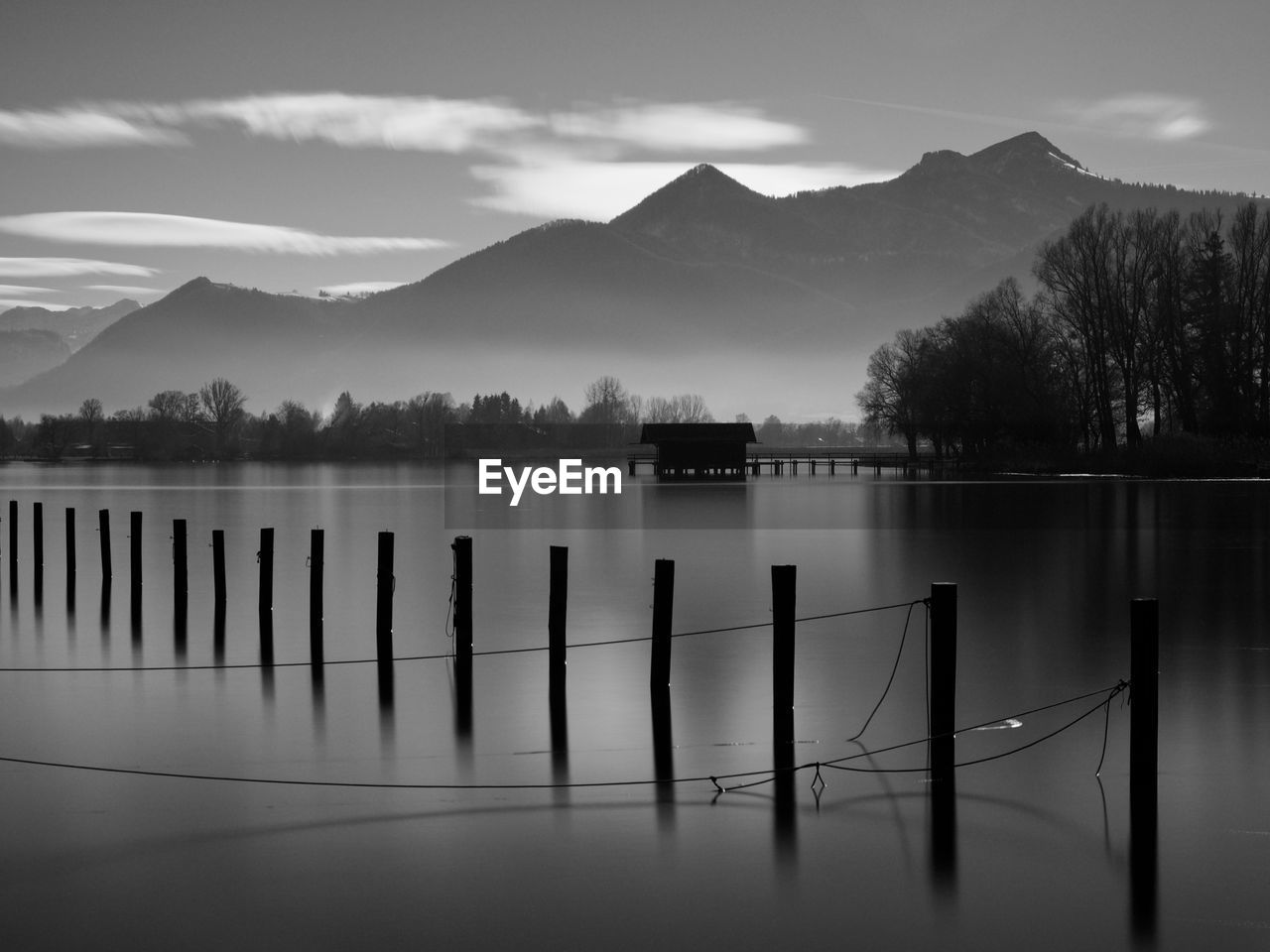 Wooden posts in lake against sky