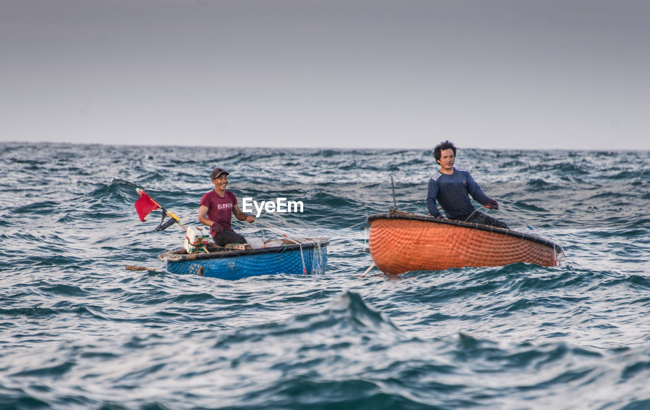 PEOPLE ON BOAT IN SEA AGAINST SKY