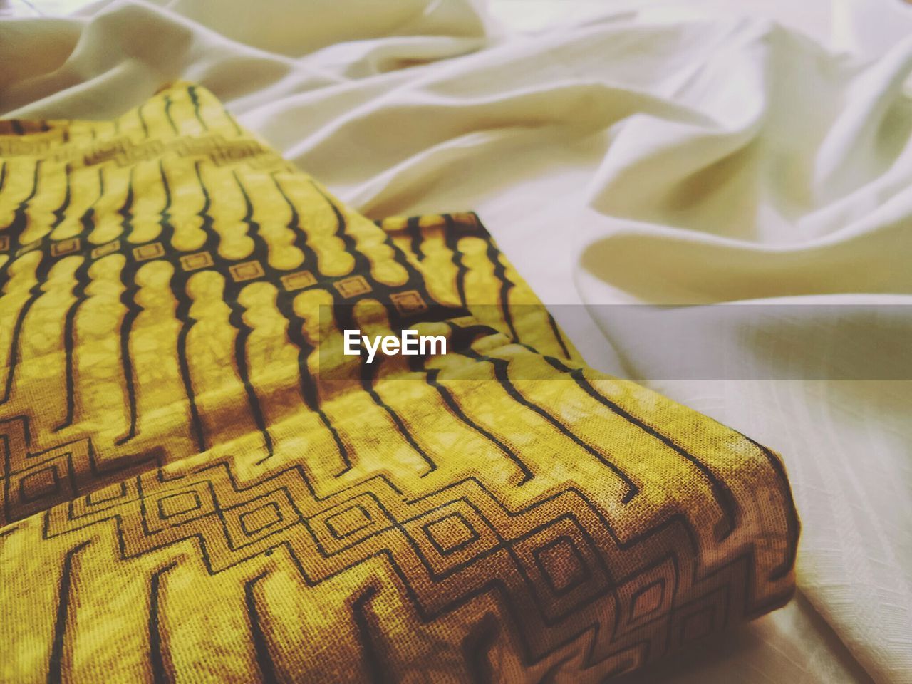 Close-up of yellow pillow on bed at home