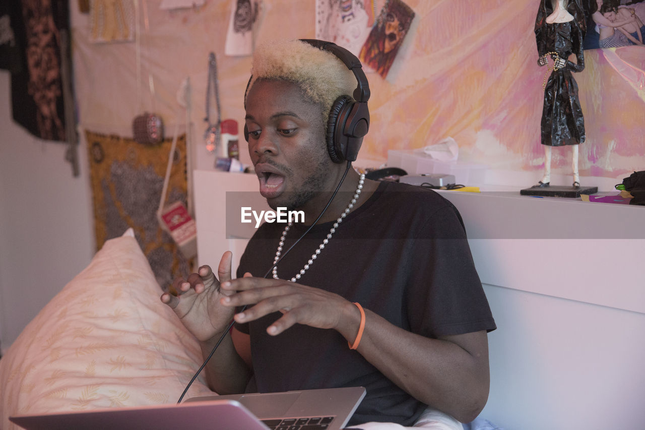 A young man wearing headphones with a laptop