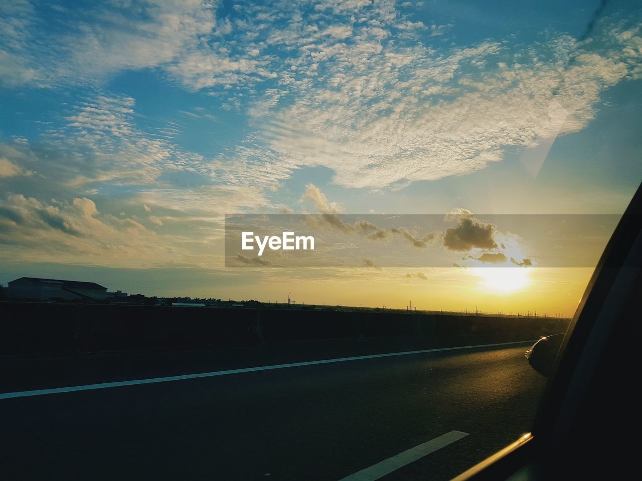 ROAD AGAINST SKY SEEN THROUGH CAR WINDSHIELD DURING SUNSET