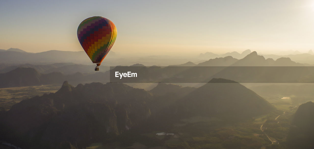 Hot air balloon flying over mountains against sky