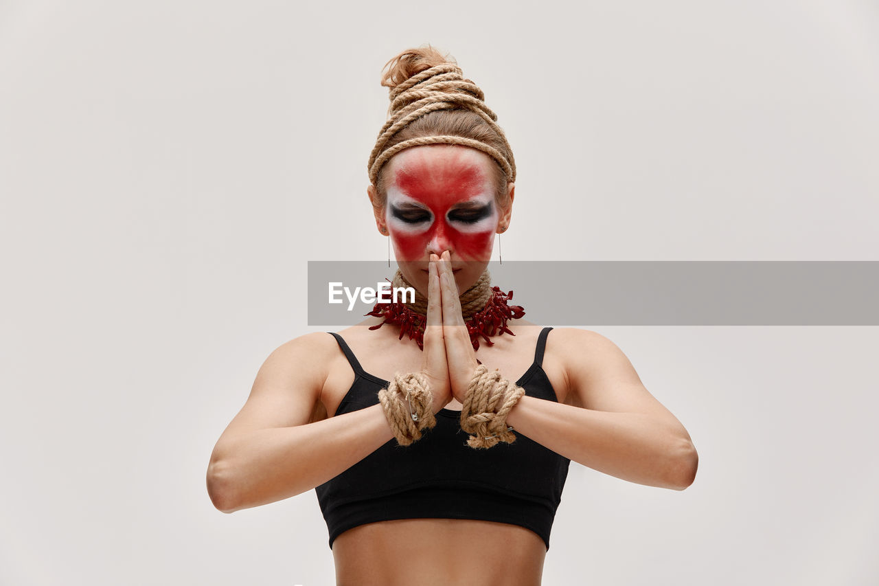 low angle view of young woman wearing sunglasses while standing against white background