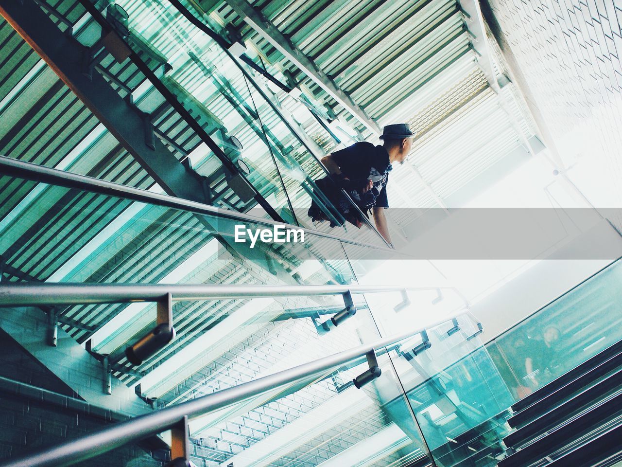 Low angle view of man standing by railing of staircase