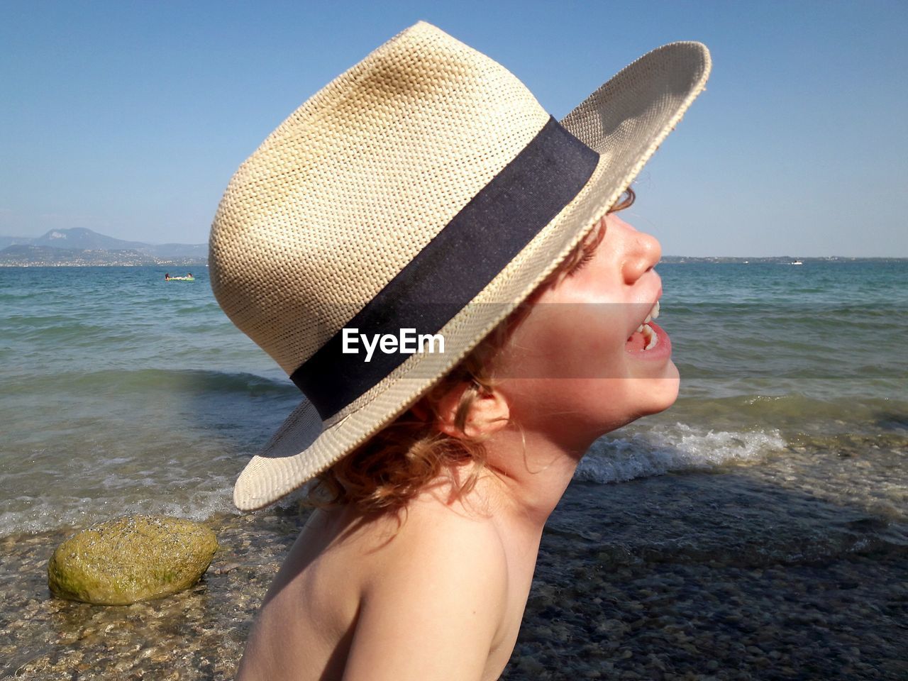 Smiling boy wearing hat against sea