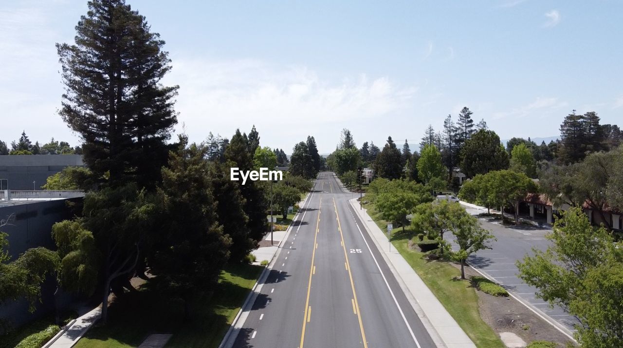 Aerial drone view of road amidst trees against sky