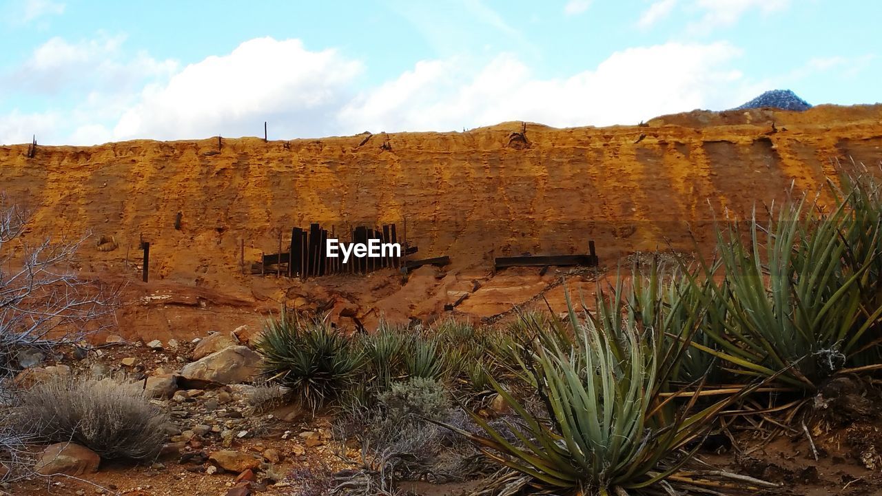 Rocky cliff on semi-arid landscape against sky