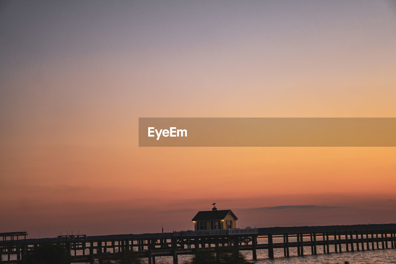 SILHOUETTE PIER ON SEA AGAINST ORANGE SKY