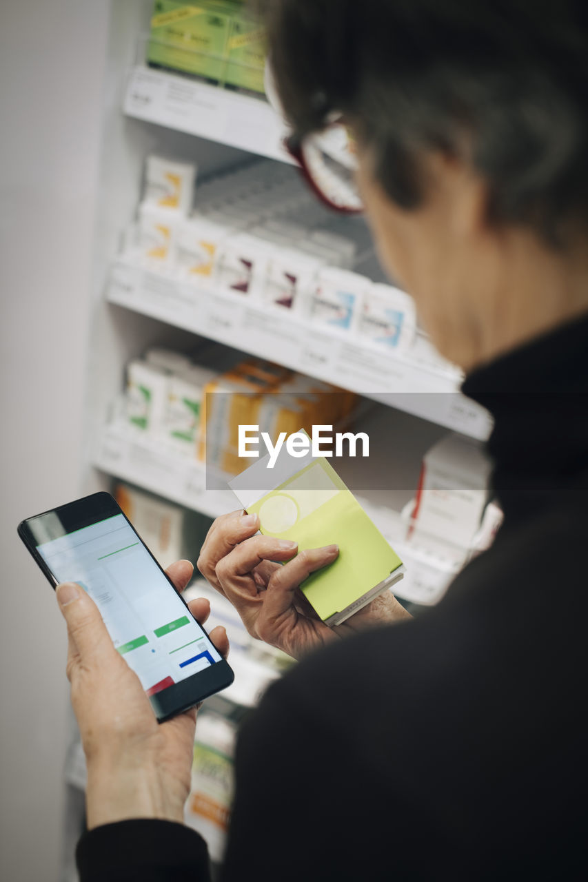 High angle view of senior woman using smart phone for checking medicine at store