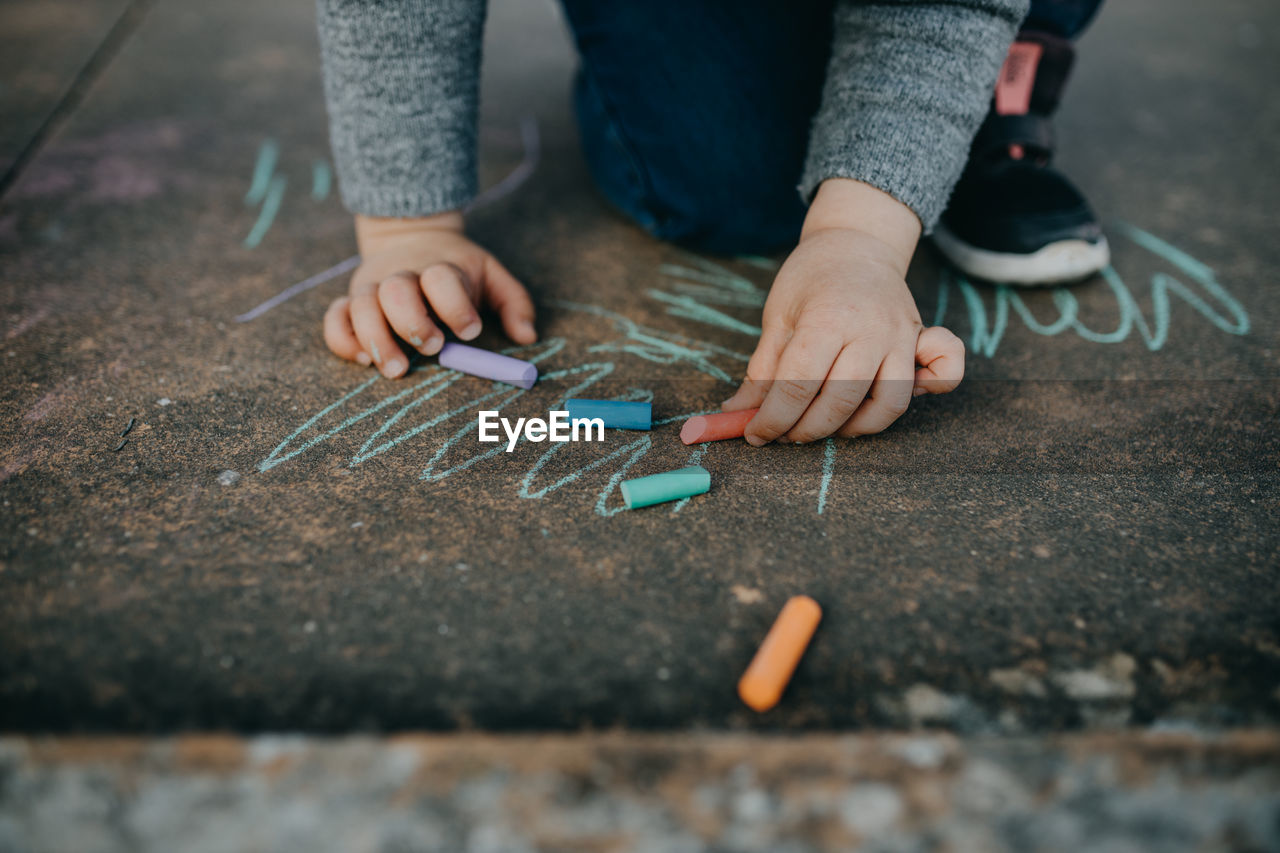 Child drawing with colored chalk on the floor