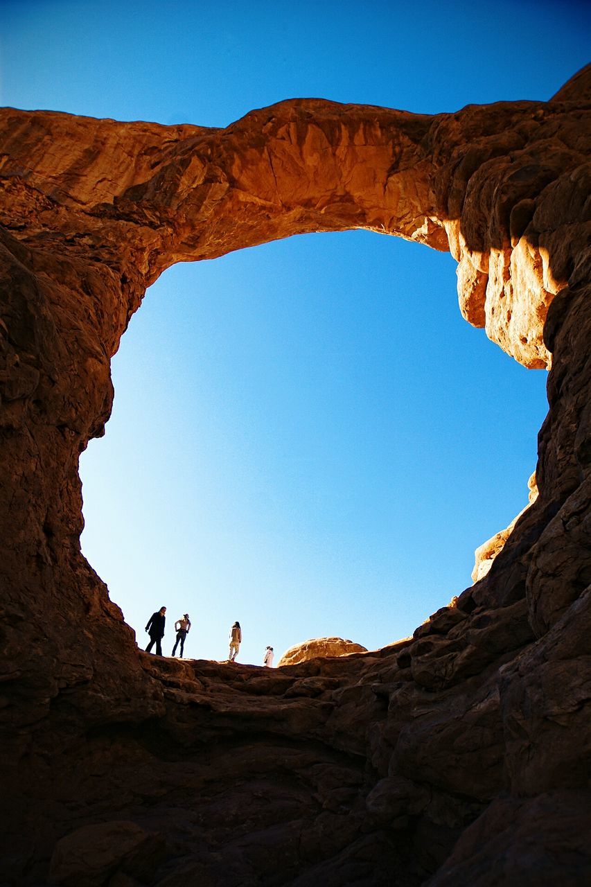 Low angle view of hole in rock against clear sky