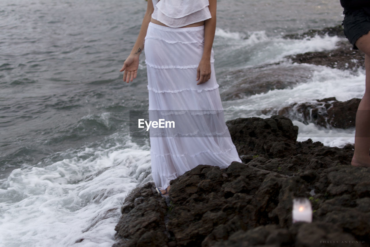 Low section of woman standing on sea shore