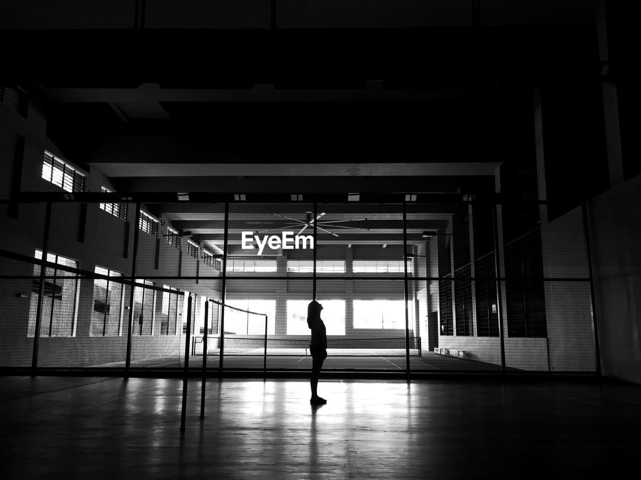 Silhouette of woman standing at tennis court