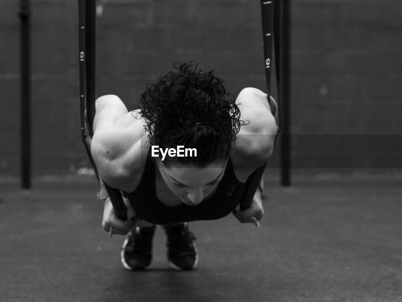 Exercising woman holding gymnast rings in black and white