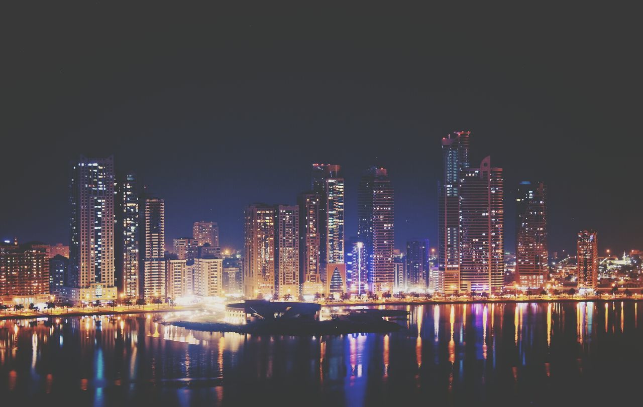 Illuminated buildings against clear sky during night