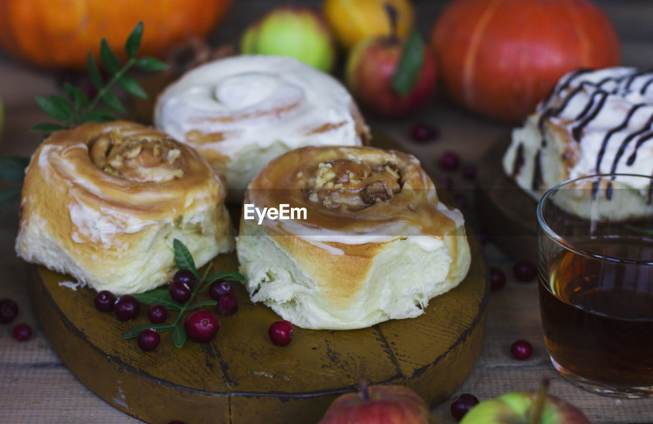 Fresh baked cinnamon rolls with frosting, apples and tea on the shabby background