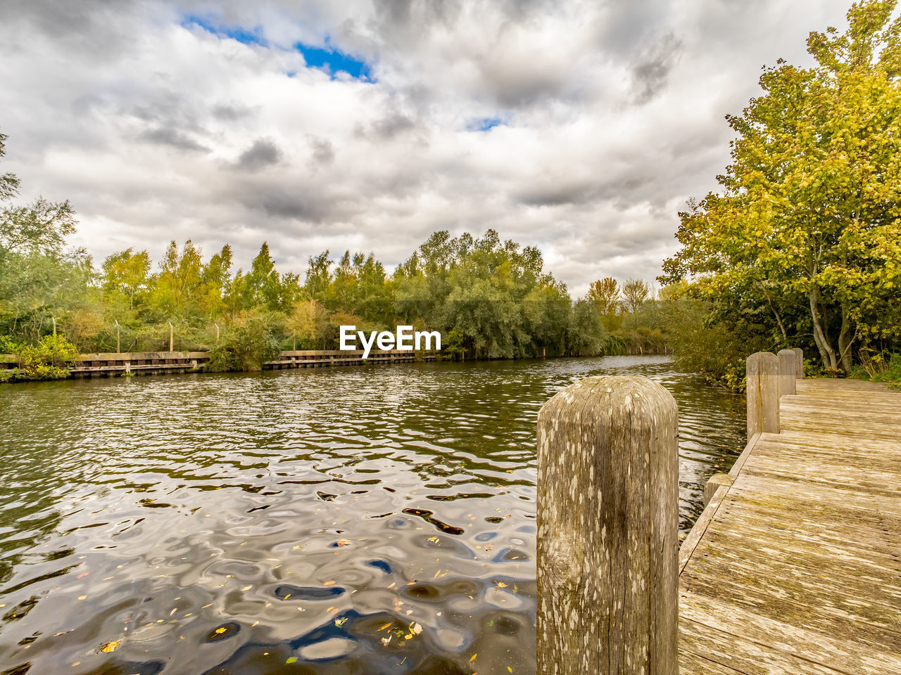 WOODEN POSTS ON LAKE AGAINST SKY