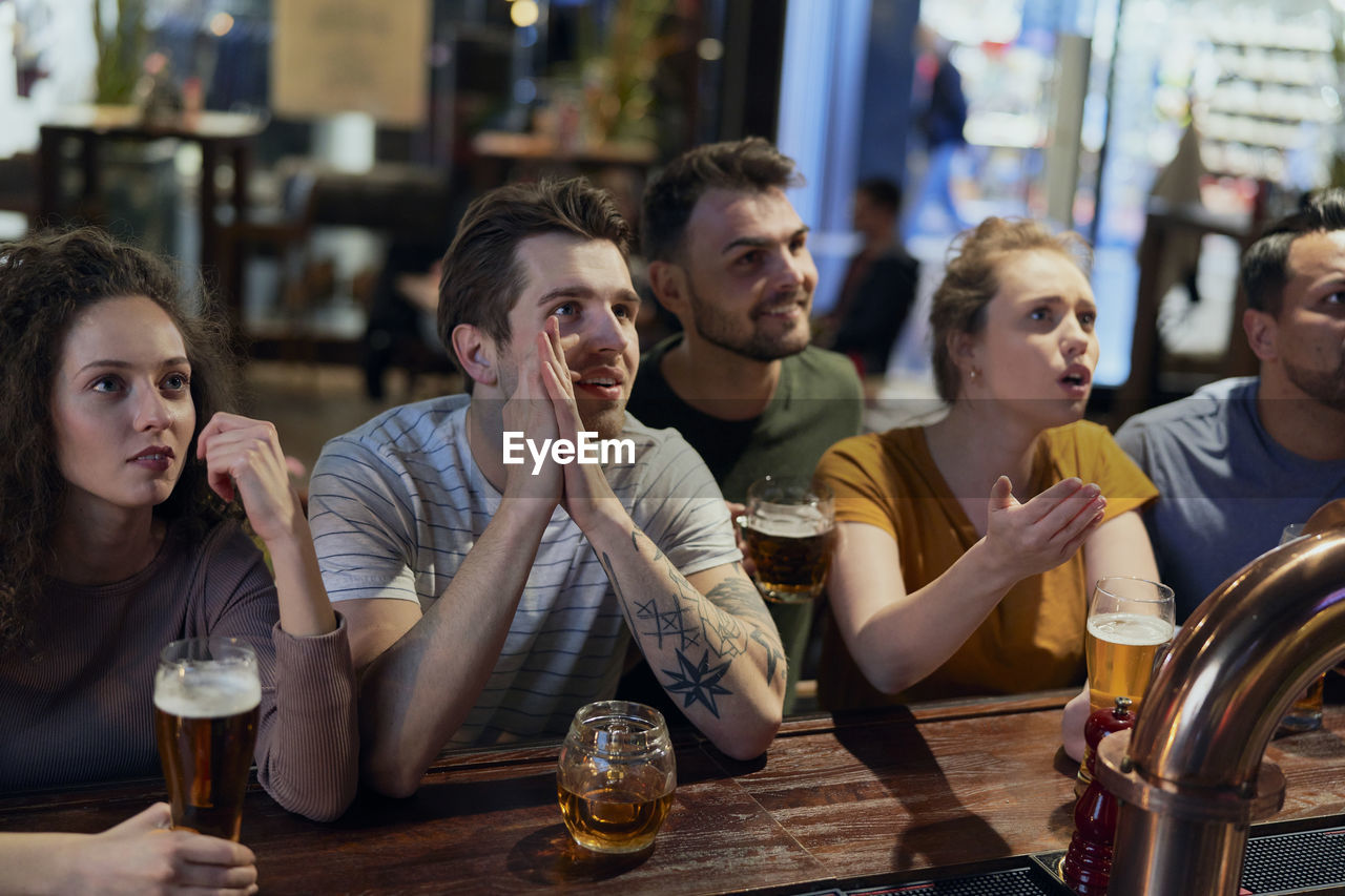 Happy friends watching soccer match at bar