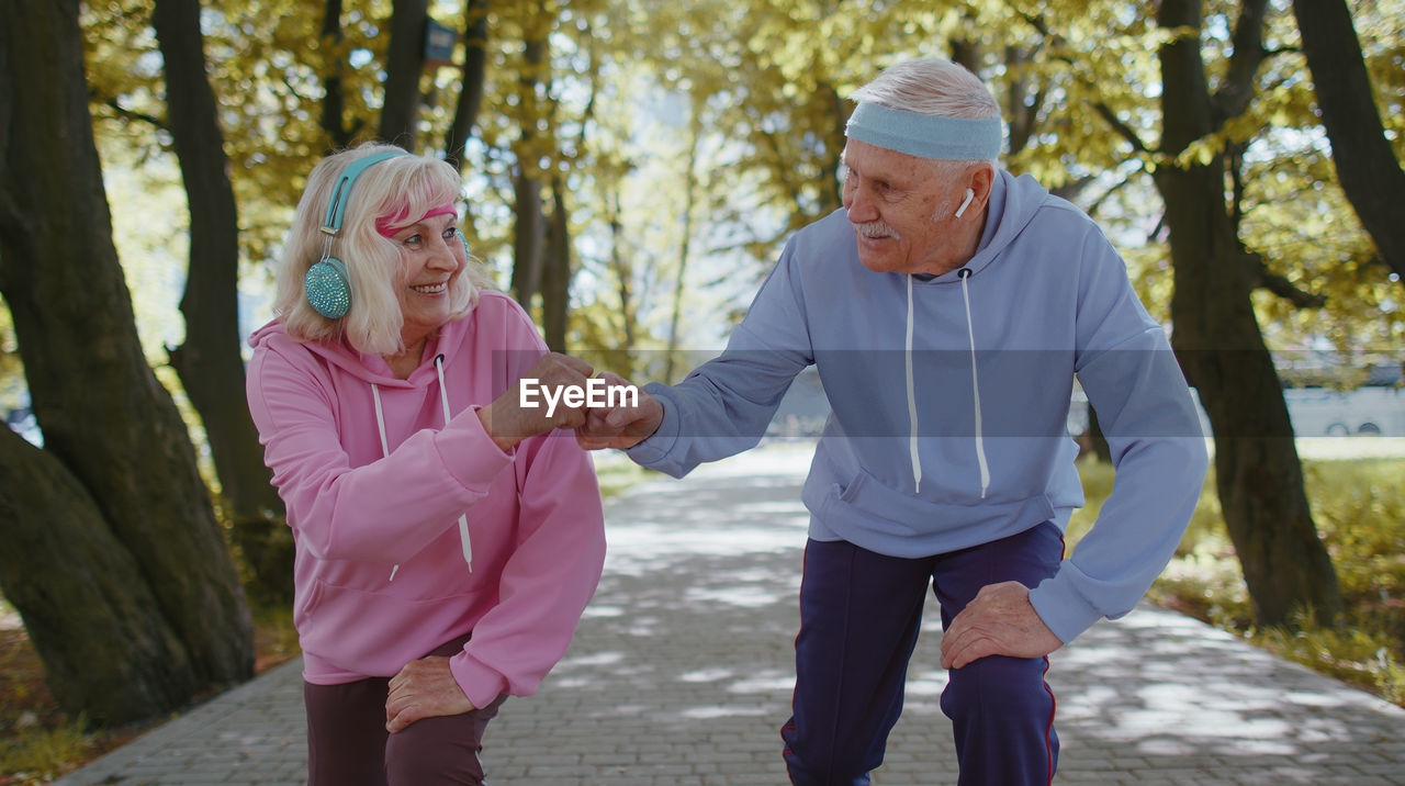 Senior man and woman bumping fists in park