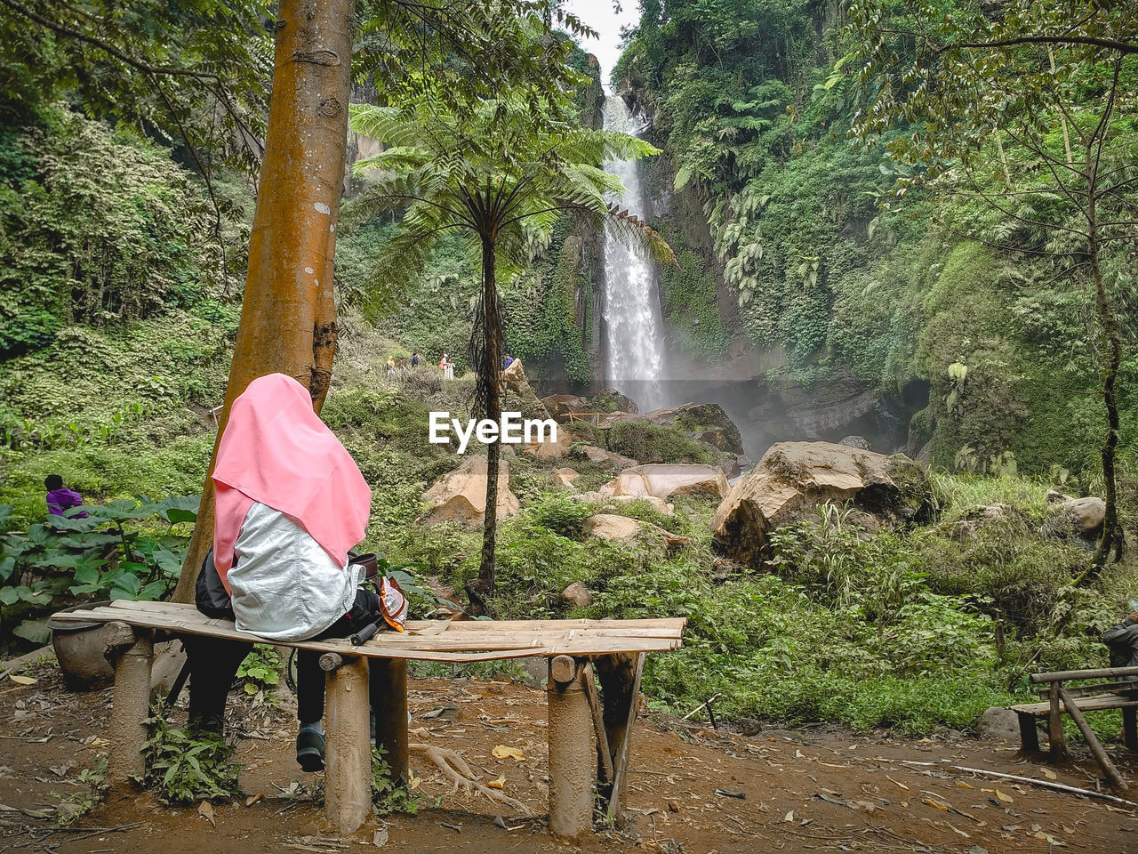 REAR VIEW OF MAN LOOKING AT WATERFALL