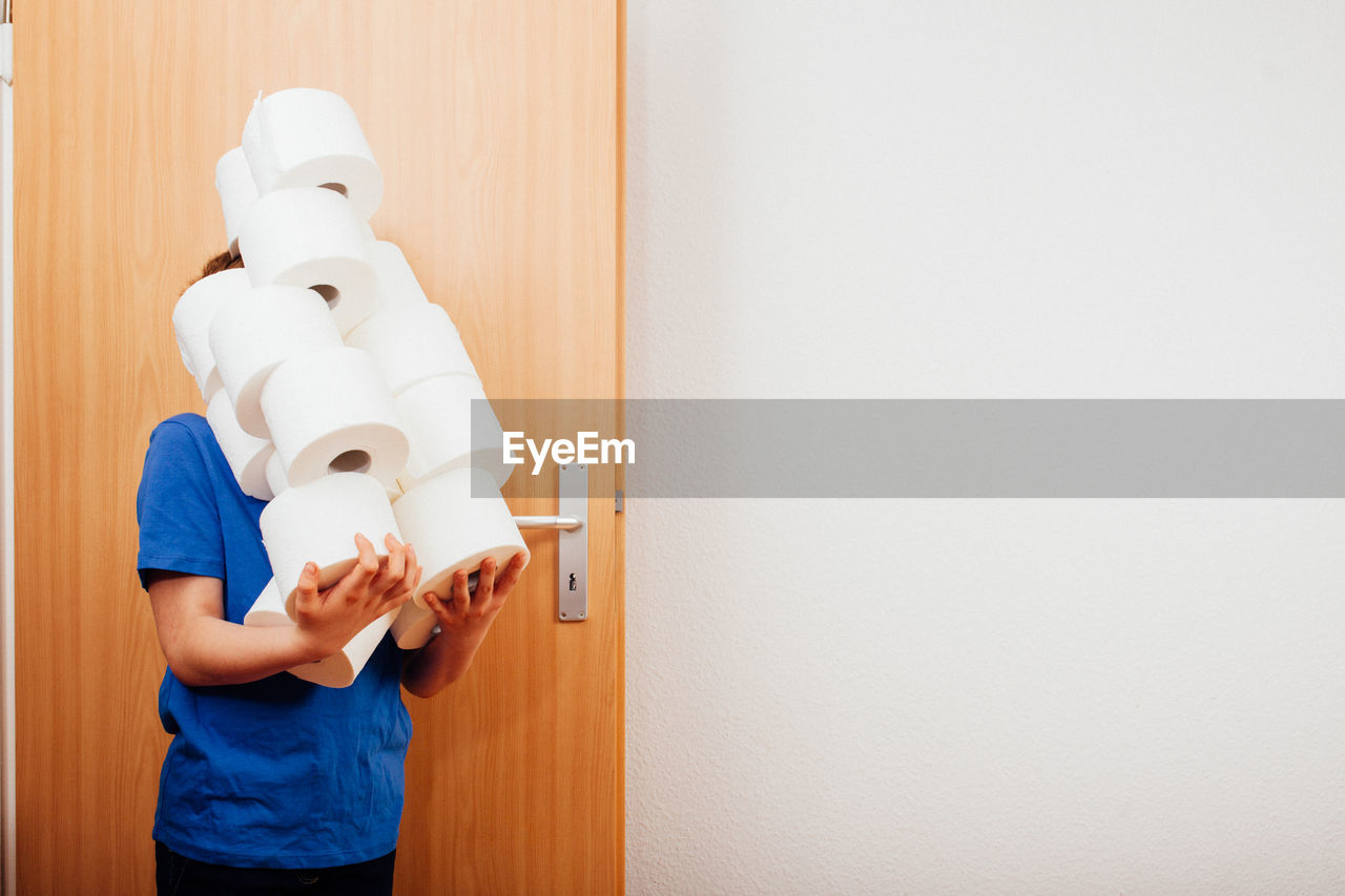 Boy with tissue roles standing by door