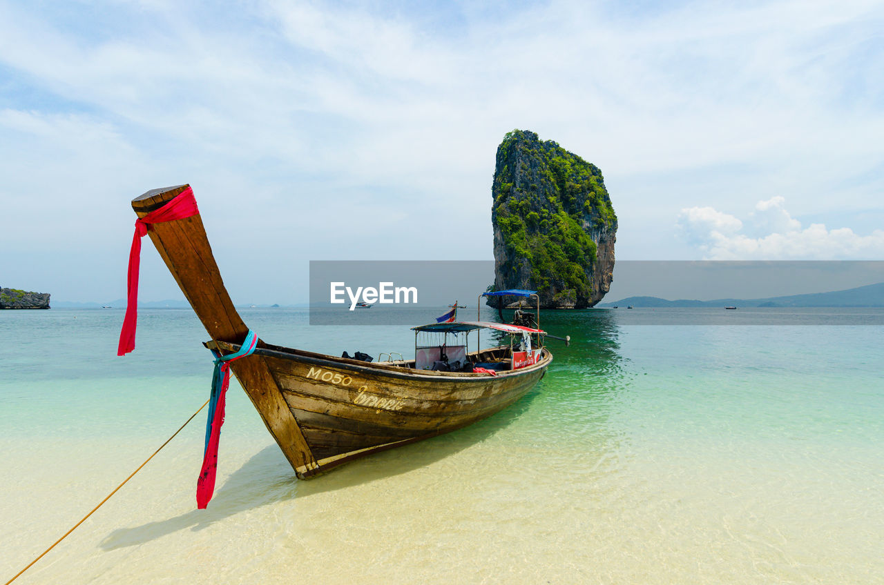 BOAT MOORED ON SHORE AGAINST SKY