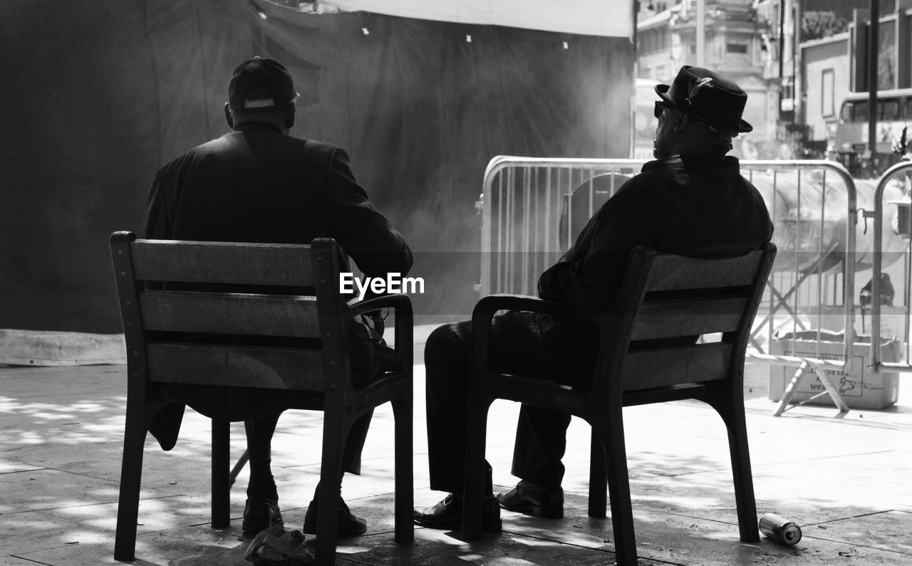 Rear view of men sitting on chairs on street