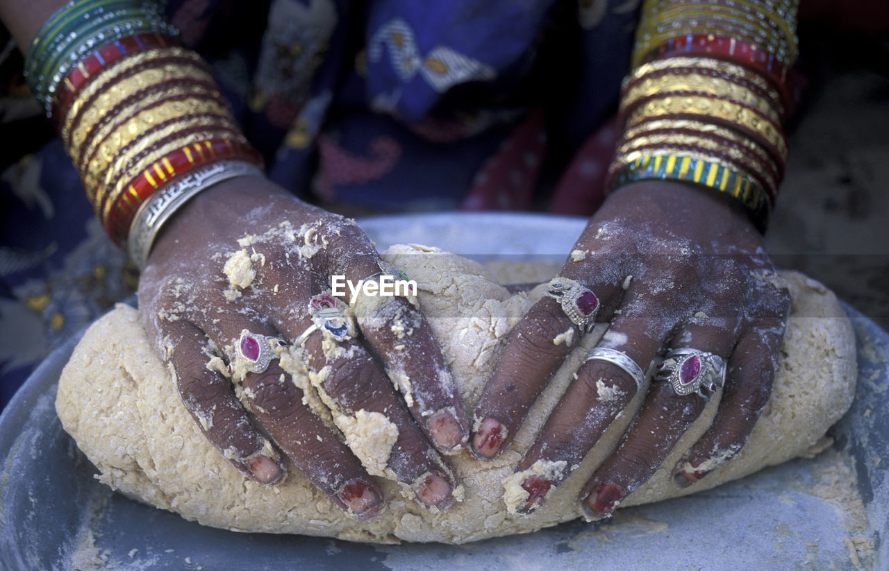 Close-up of hands with rings preparing dough