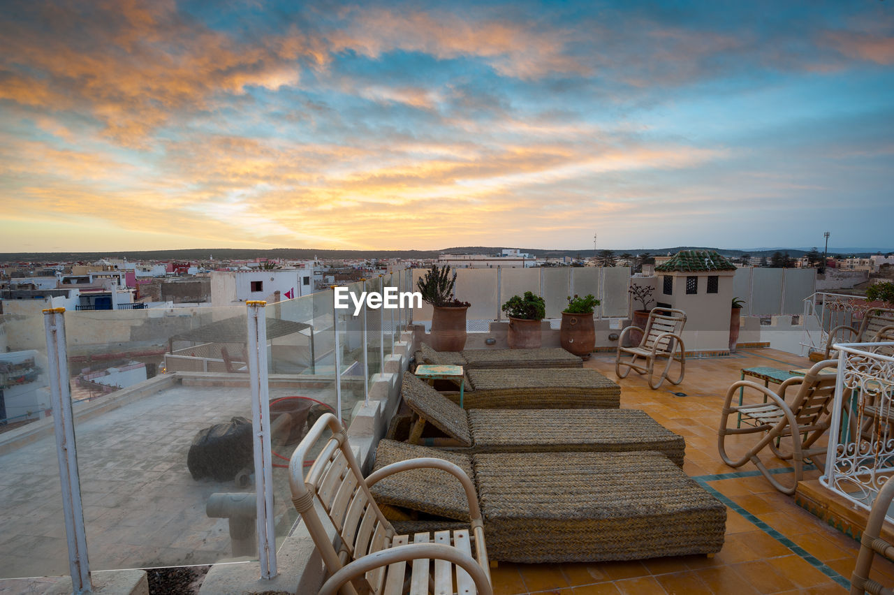 EMPTY CHAIRS AND TABLES AGAINST SKY AT SUNSET