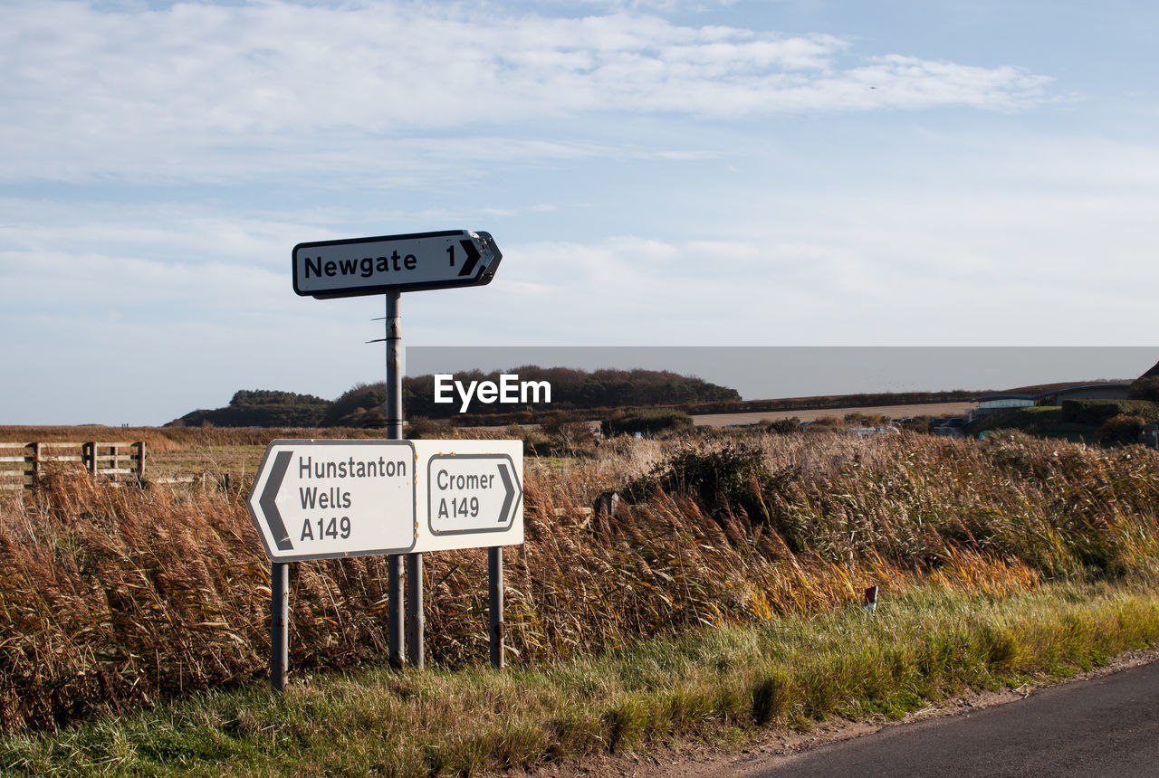 INFORMATION SIGN ON ROAD AMIDST FIELD