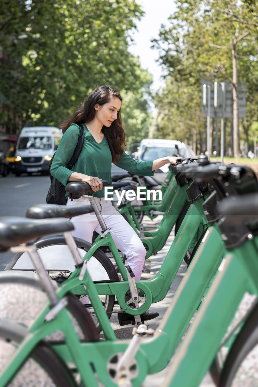 Woman renting bicycle at parking station