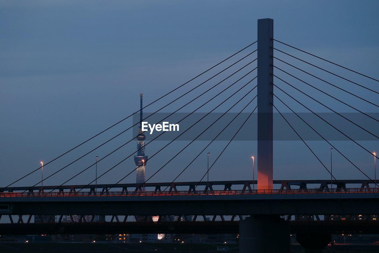 Low angle view of suspension bridge against cloudy sky