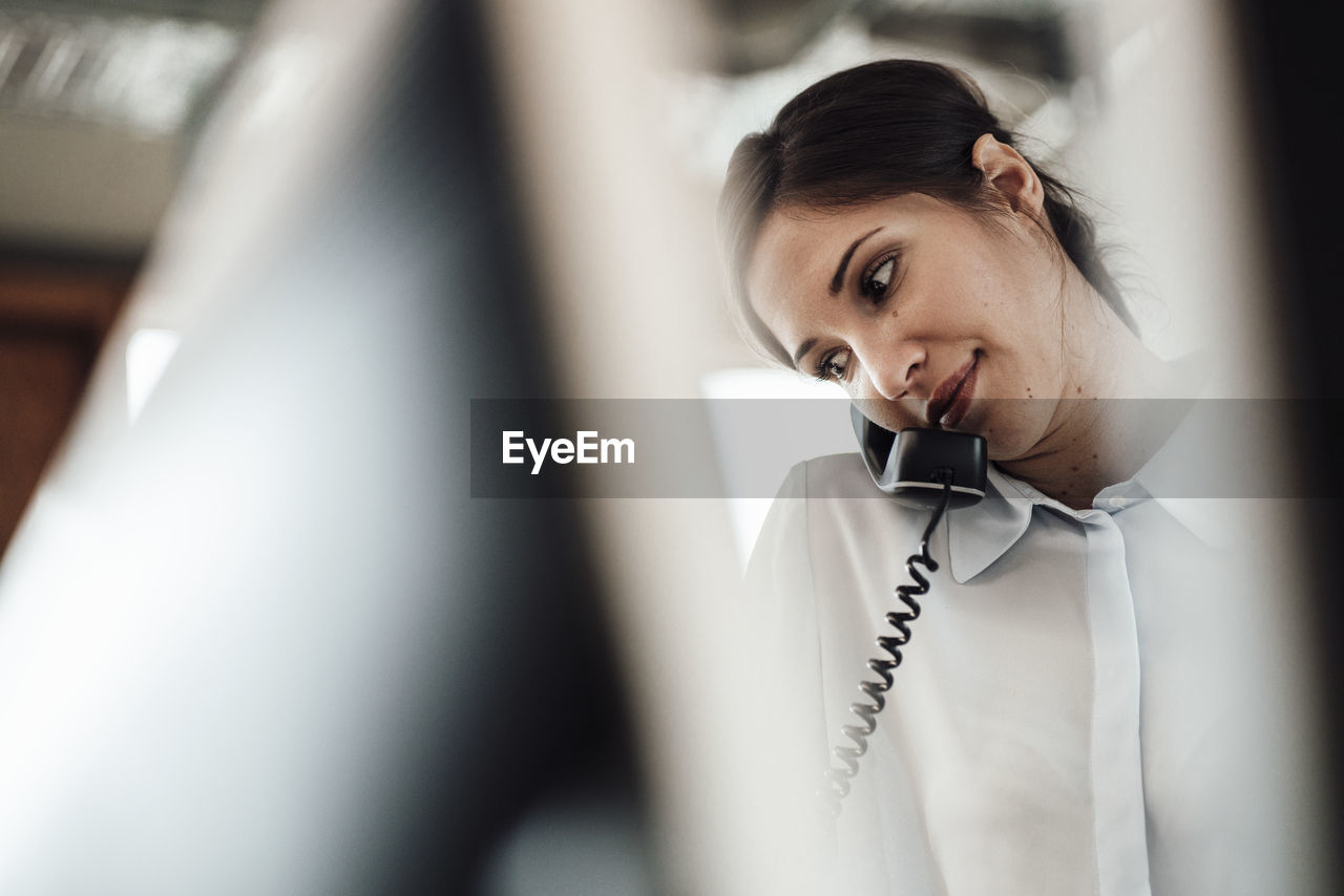 Female entrepreneur talking on landline phone at office