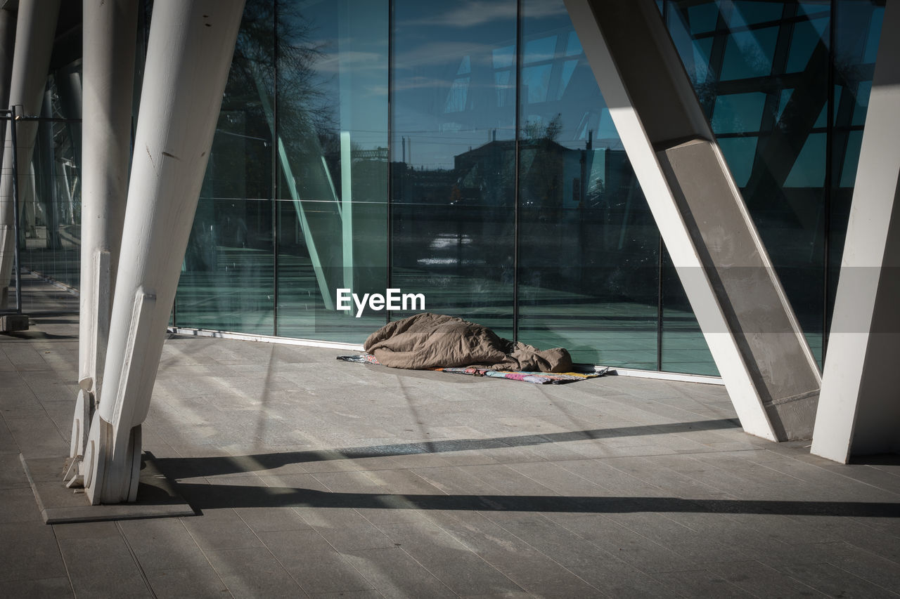 Homeless sleeping under warm blankets over a modern design bridge.