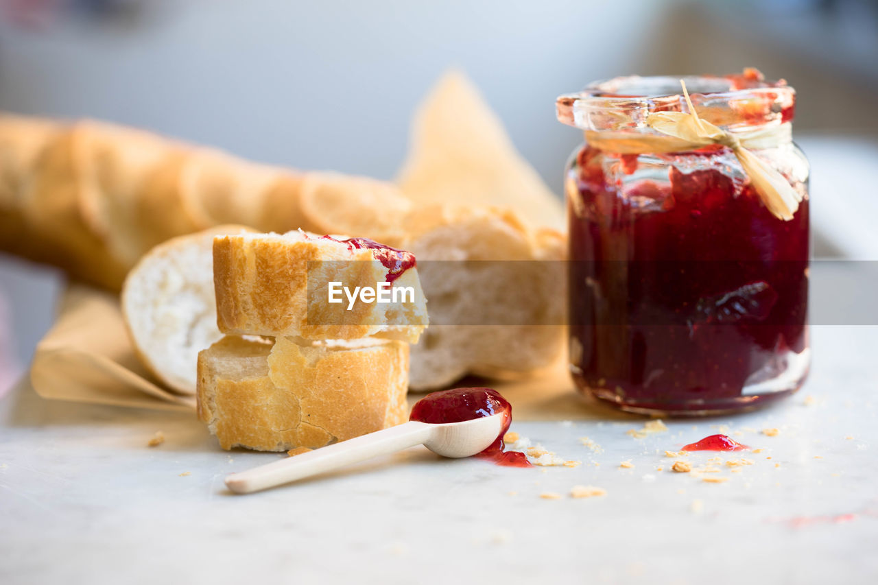 Baguette and strawberry jam on table