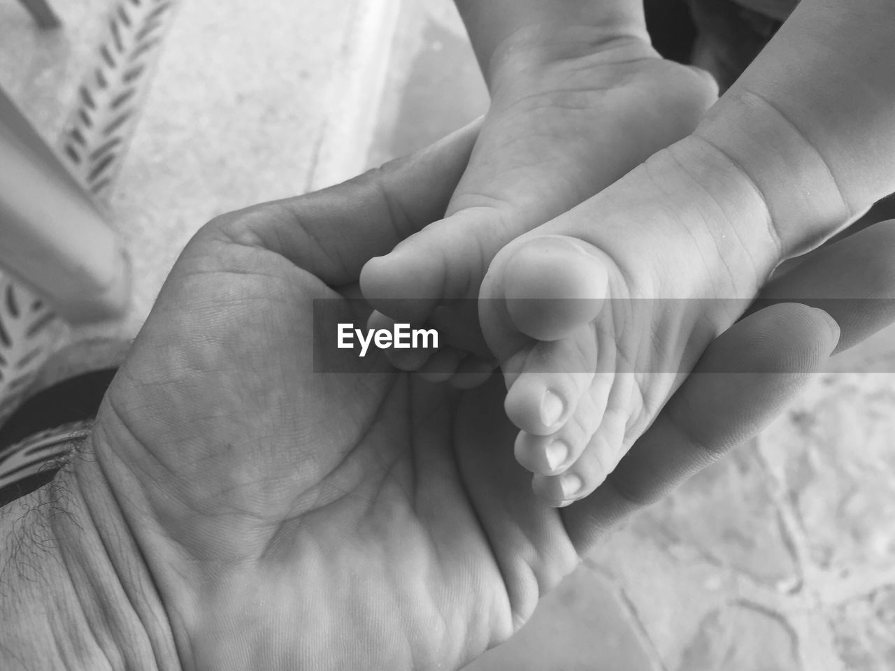 Cropped hand of man holding newborn child feet at home