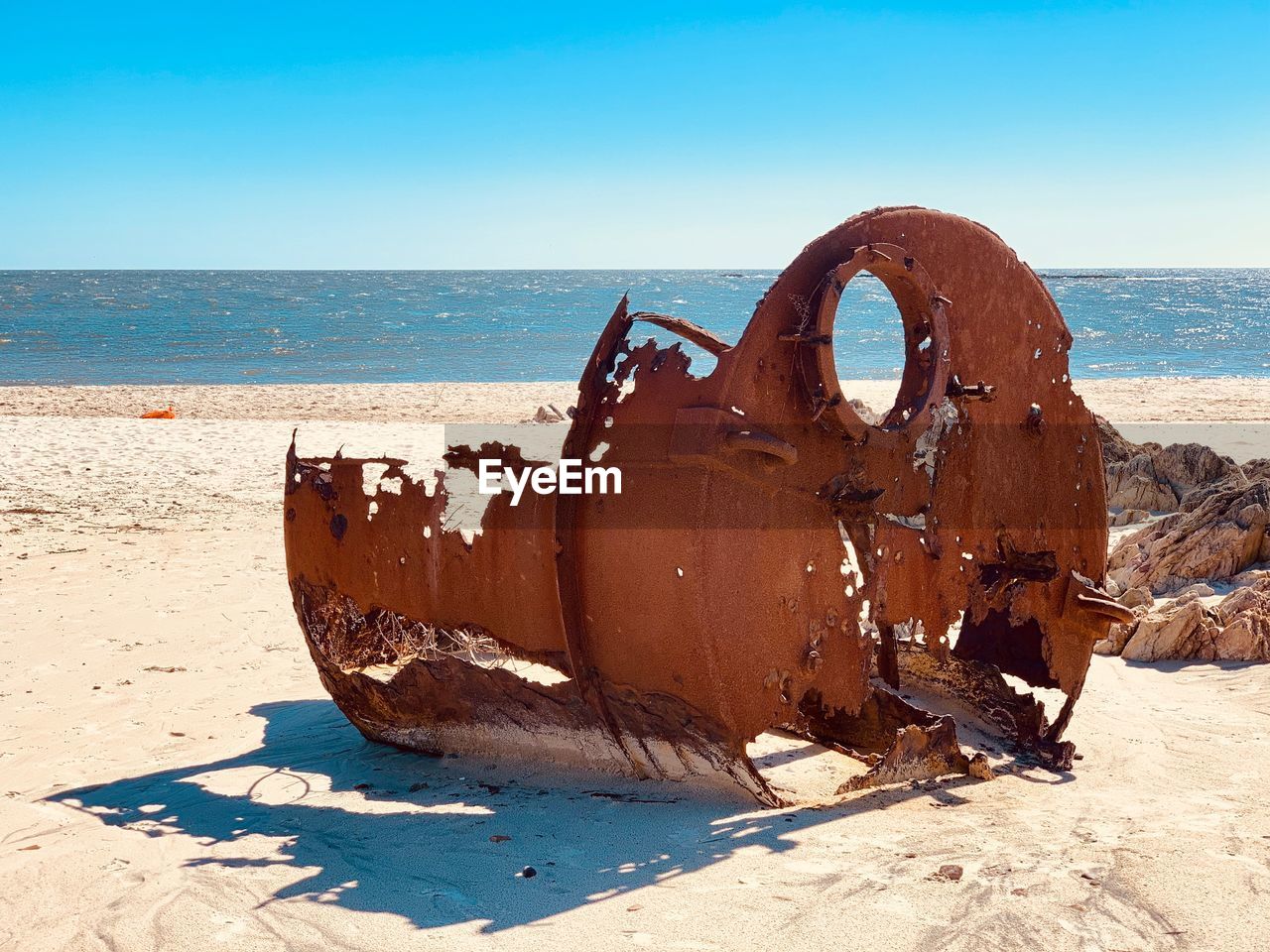 OLD RUSTY WHEEL ON BEACH AGAINST SKY