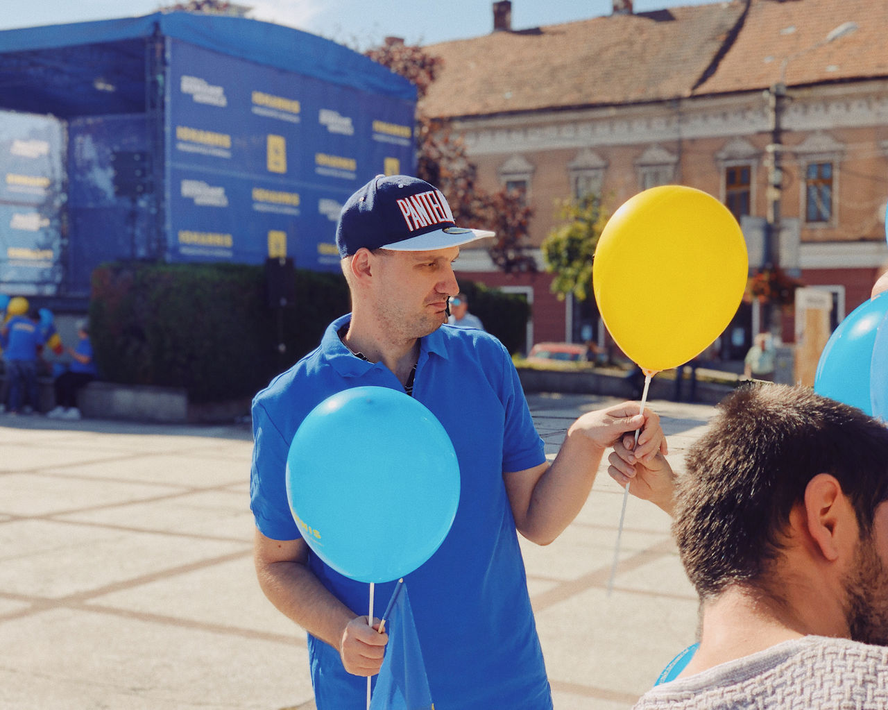 MAN HOLDING BALLOONS WITH UMBRELLA