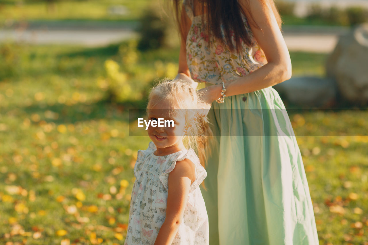 Daughter with mother on grass in park