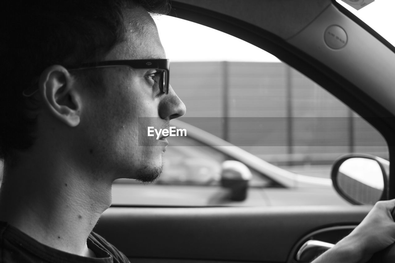 Close-up of young man driving in car