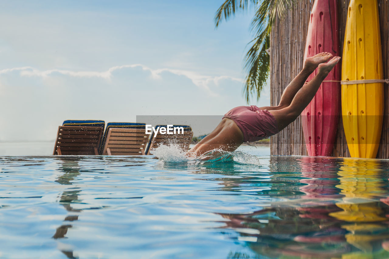 Man on vacation play in outdoor swimming pool jumping