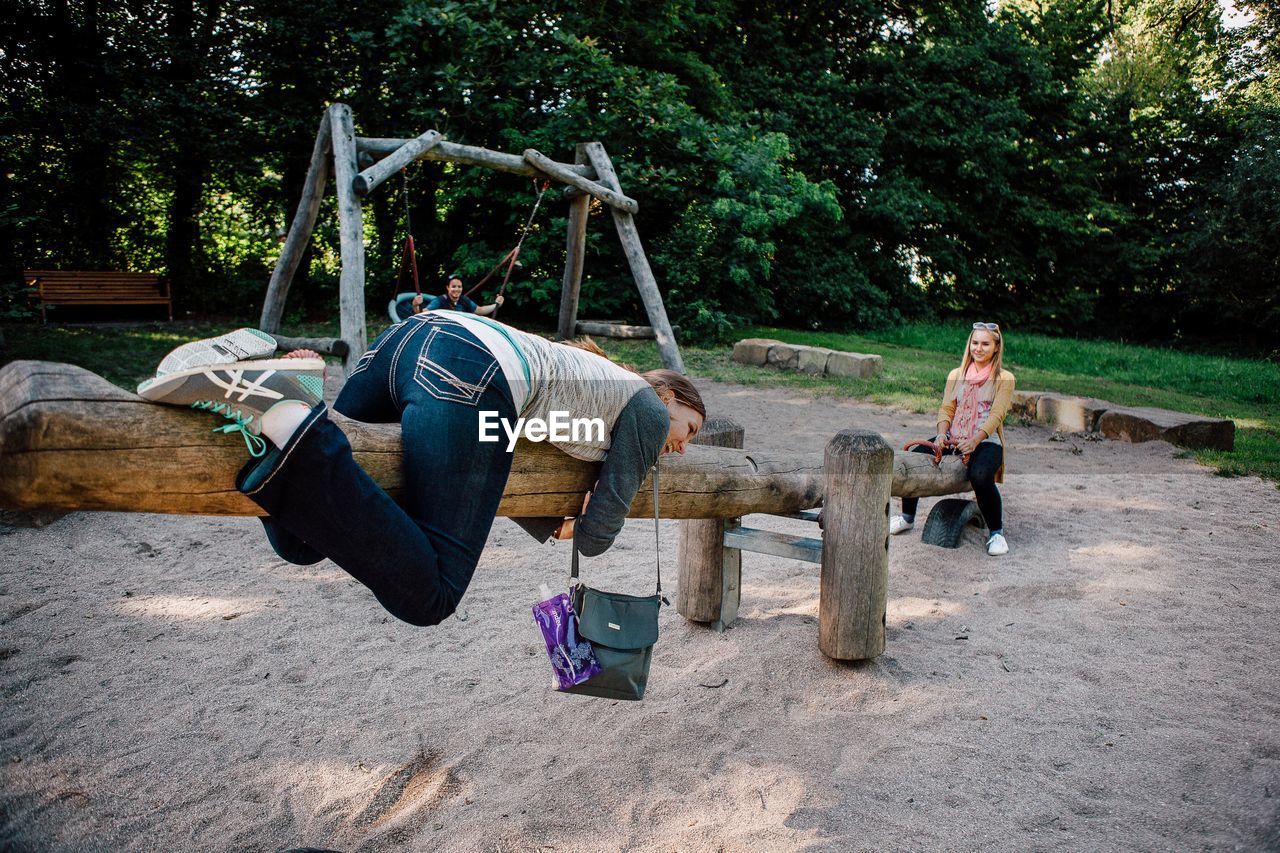 Young female friends playing on wooden seesaw at park