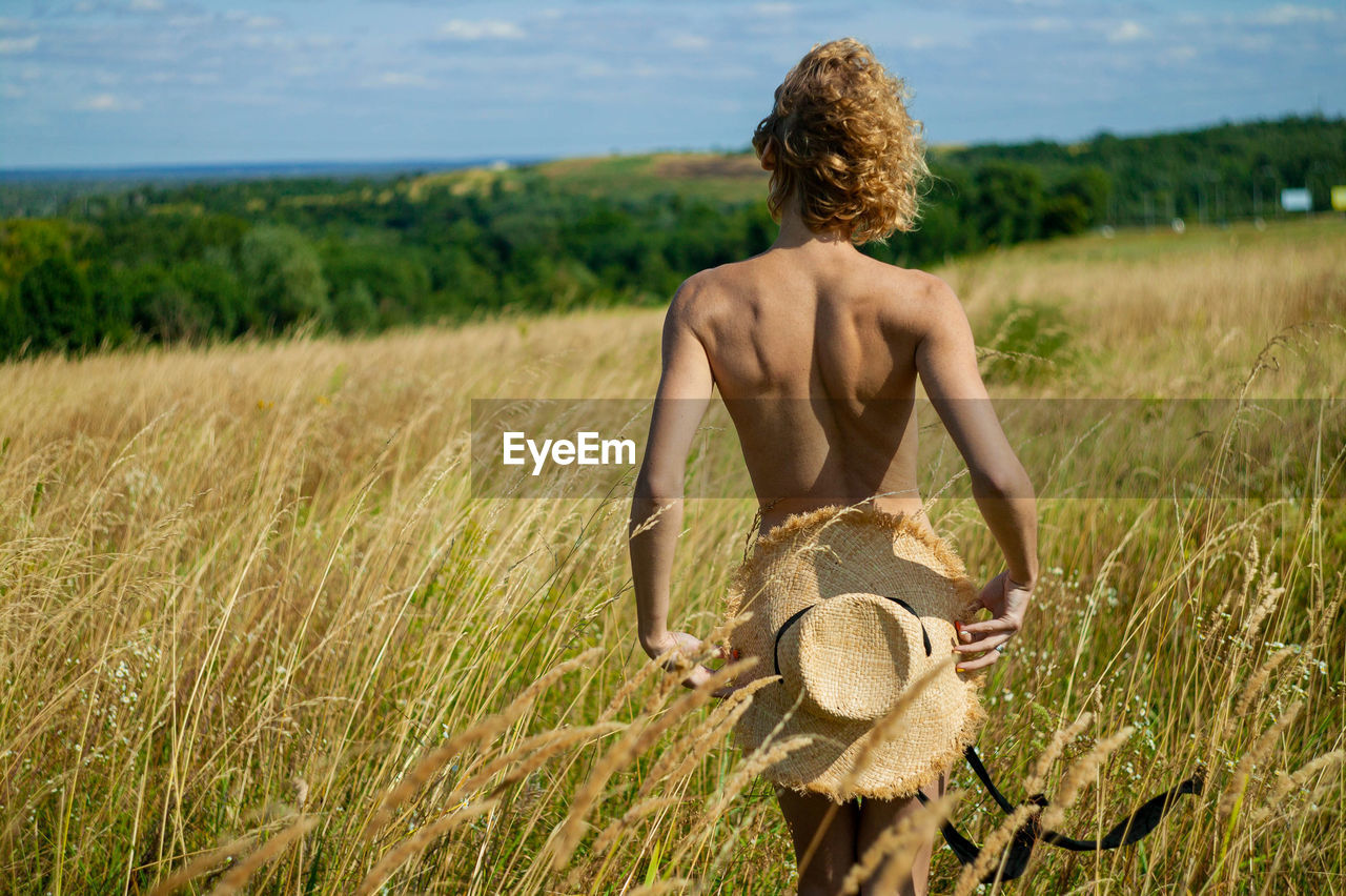 Blonde girl with naked back in summer field
