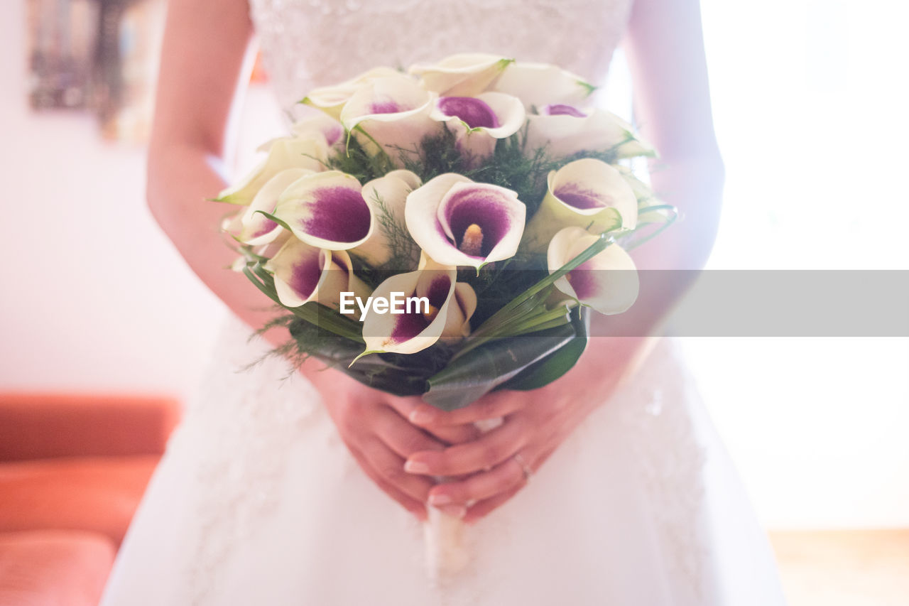 Midsection of bride holding bouquet during wedding
