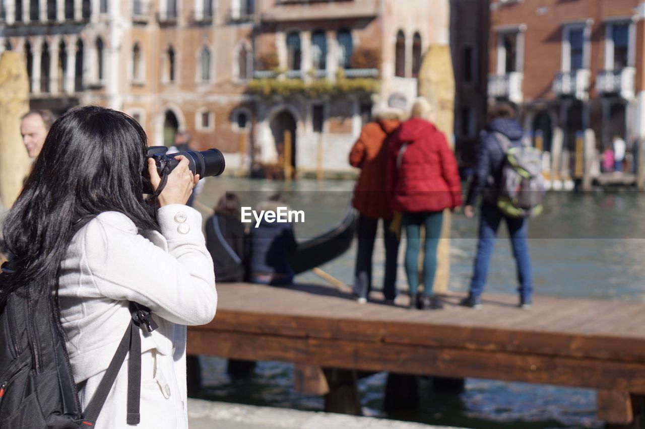 REAR VIEW OF WOMAN PHOTOGRAPHING WITH REFLECTION