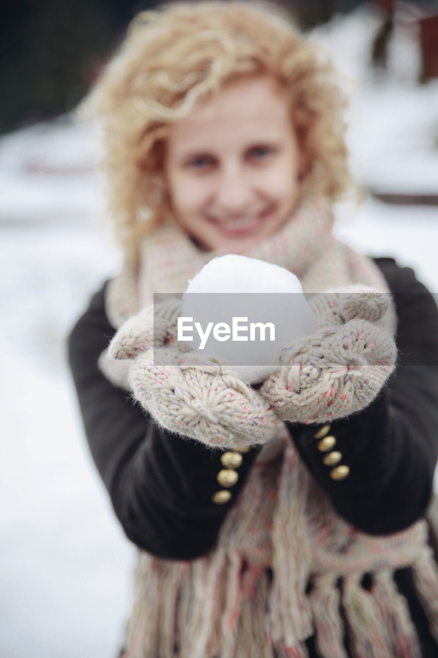 Portrait of smiling young woman holding snowball