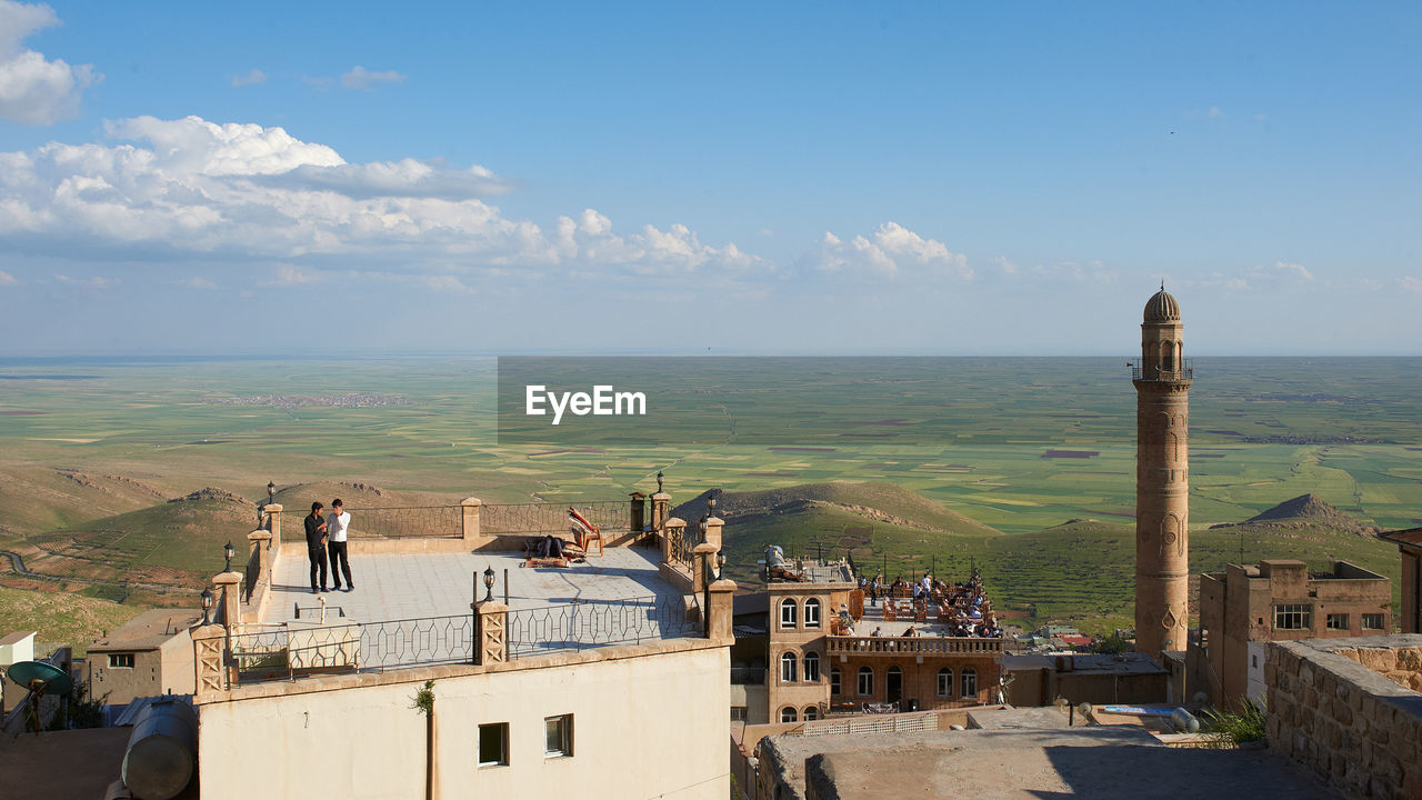 HIGH ANGLE VIEW OF BUILDINGS IN CITY AGAINST CLOUDY SKY