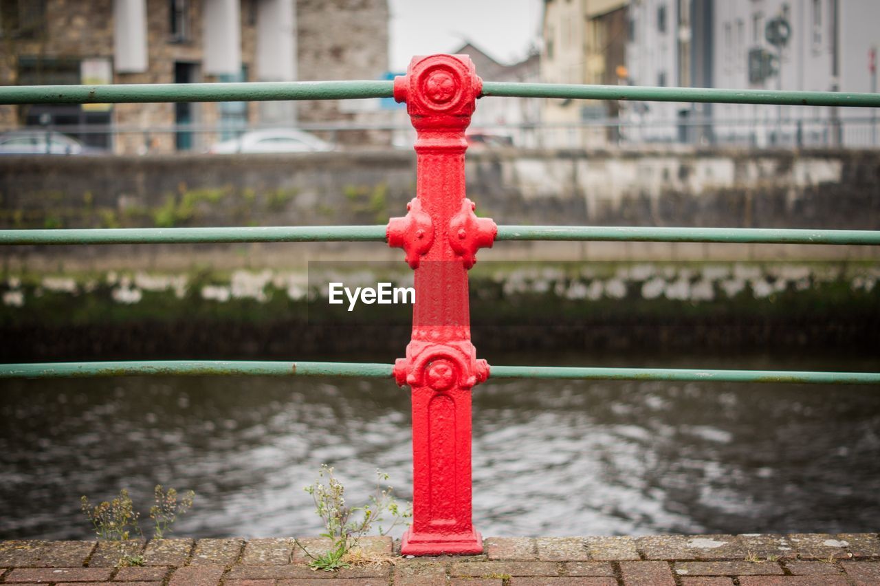 CLOSE-UP OF RED RAILING OVER RIVER