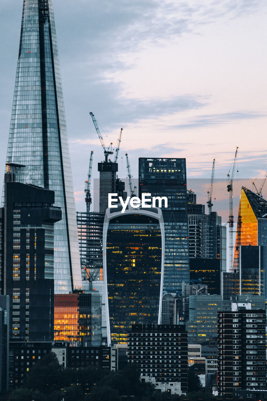 Modern buildings in city against sky during sunset