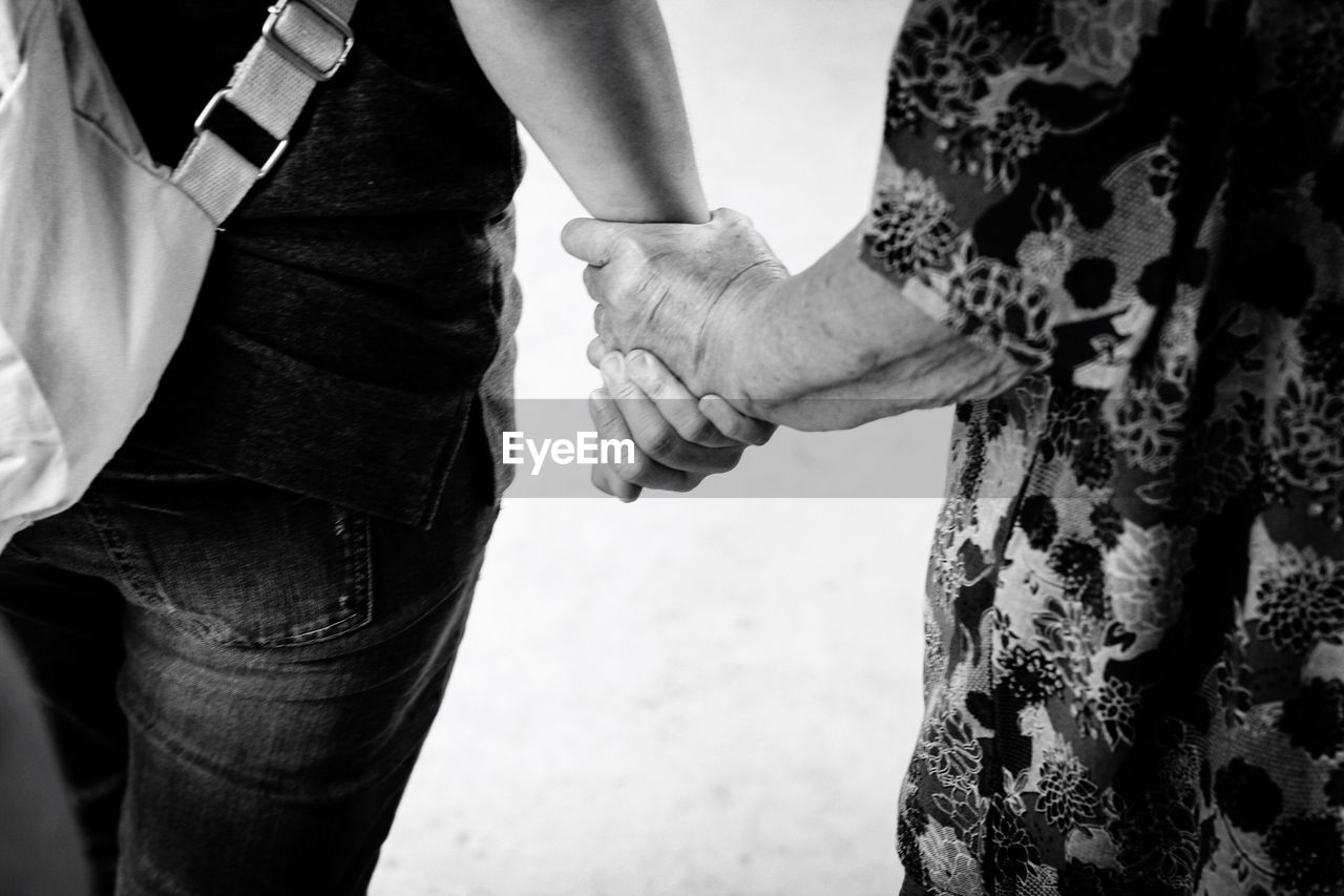 Adult woman and senior one holding hands